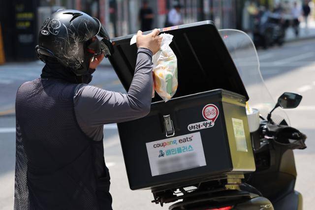 19일 서울 시내 식당가에서 한 배달기사가 음식을 오토바이에 넣고 있다. 뉴시스