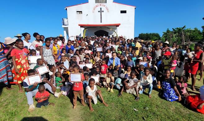 최봉진 선교사가 마다가스카르 ‘오차로구미교회’ 앞에서 성도들과 함께 기념사진을 찍고 있다. 앞줄의 아이들이 세례 증서를 손에 들고 환하게 웃고 있다. 최 선교사 제공