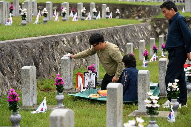참전용사 기리는 후손  : 6·25전쟁 75주년인 25일 오전 국립서울현충원에서 1953년 6월 9일 인제 전투에서 전사한 홍순석 씨 묘에 합장된 서여순 씨의 손자 원형문(왼쪽) 씨가 묘비를 닦고 있다.  윤성호 기자