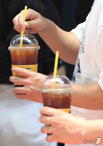 서울 시내에 위치한 저가 브랜드 커피 매장 앞에서 시민들이 커피를 들고 이동하고 있다. 2024.7.1/뉴스1 ⓒ News1 임세영 기자