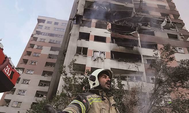 6월 13일 오전 이스라엘 공군의 공습으로 파괴된 이란 수도 테헤란의 아파트에 출동한 소방대원이 동료에게 도움을 요청하고 있다. /사진 AP연합