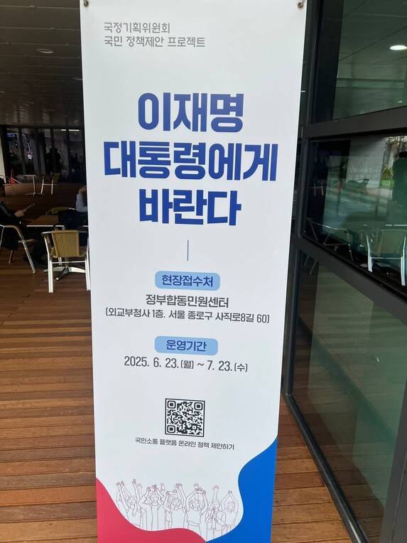 지난 24일 서울 종로구 국정기획위원회 출입구 옆에 온라인으로 국정기획위원회에 정책을 제안할 수 있는 ‘모두의 광장’ 누리집으로 연결되는 큐알코드가 그려진 입간판이 세워져 있다. 최현수 기자