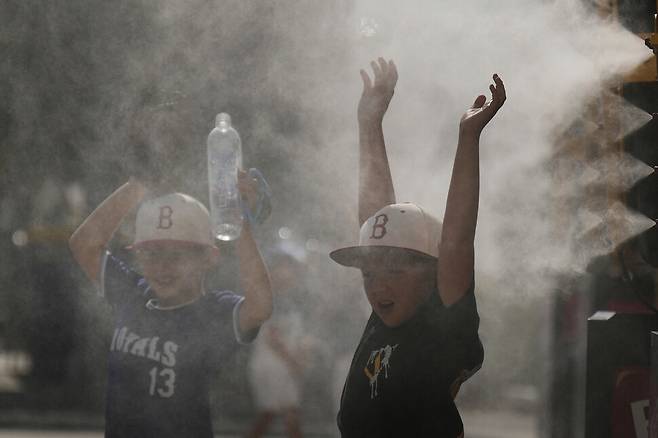 지난 25일(현지시각) 미국 미주리주 캔자스시티에 있는 카우프만 스타디움에서 아이들이 야구 경기를 앞두고 분사기에서 나오는 안개를 맞으며 더위를 식히고 있다. 캔자스시티/AP 연합뉴스
