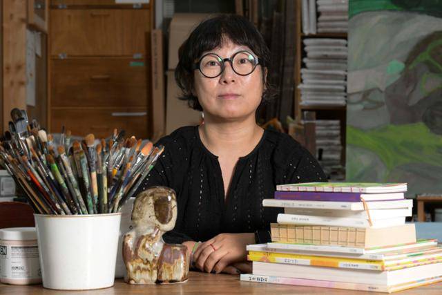 "내 그림의 베이스는 문학"이라는 노석미 작가가 붓과 자신의 펴낸 책들과 함께 포즈를 취하고 있다. 강예진 기자