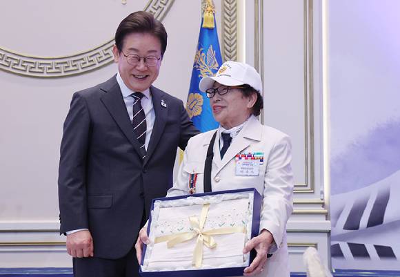 이재명 대통령이 27일 청와대 영빈관에서 열린 '호국 보훈의 달, 대통령의 초대' 행사에서 특별 초청대상자인 이춘자 씨에게 광목이불을 선물한 뒤 기념촬영을 하고 있다. 이번 행사에는 국가유공자 및 유족, 보훈단체장, 특별초청자 등이 참석했다. 2025.6.27 [사진=연합뉴스]