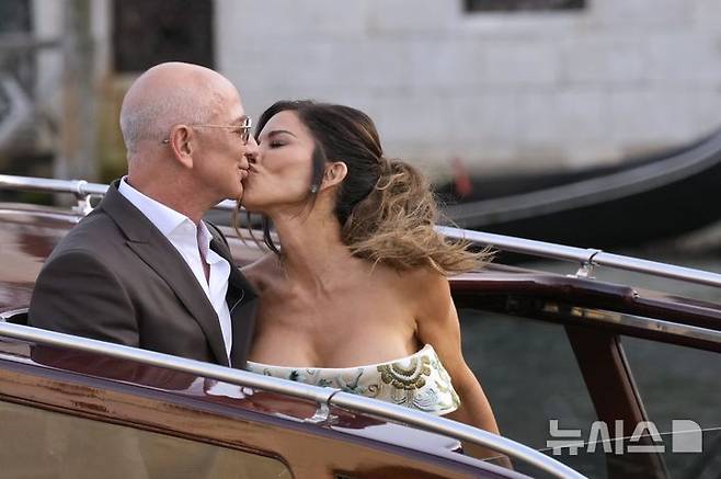 [베네치아=AP/뉴시스] 아마존 창업자 제프 베이조스와 약혼녀 로렌 산체스가 26일(현지 시간) 결혼식 전 열리는 리셉션에 참석하기 위해 이탈리아 베네치아 아만 베니스 호텔을 나서며 입을 맞추고 있다. 2025.06.27.