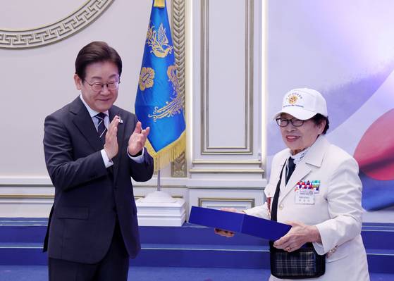 이재명 대통령이 27일 청와대 영빈관에서 열린 '호국 보훈의 달, 대통령의 초대' 행사에서 특별 초청대상자인 이춘자 씨에게 광목이불을 선물한 뒤 손뼉을 치고 있다.    이번 행사에는 국가유공자 및 유족, 보훈단체장, 특별초청자 등이 참석했다. 연합뉴스