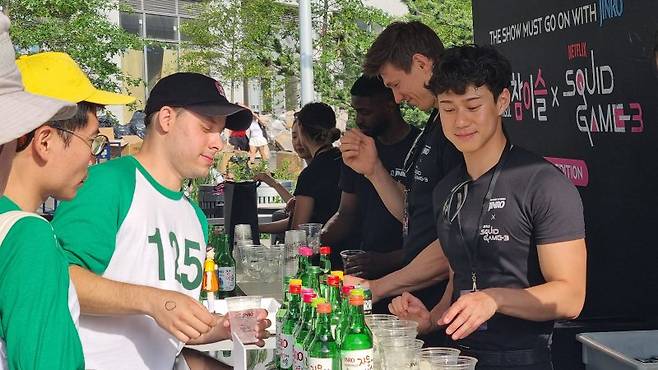 지난 20일 미국 뉴욕 도미노파크에서 열린 오징어 게임3 뉴욕팬 진로 부스에서 현지 시민들이 하이트진로의 소주와 맥주 제품을 시음하고 있다. 하이트진로 제공