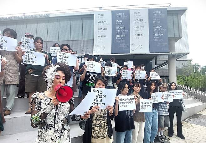 서울시립미술관의 아카이브 전시 ‘우리는 끊임없이 다른 강에 스며든다’의 도록 글 검열 사태와 관련해 지난 28일 오후 전시 장소인 서울 평창동 서울시립미술아카이브 모음동 건물 앞에서 전시에 참여 중인 일부 미술인들의 항의 퍼포먼스가 처음 펼쳐졌다. 이날 퍼포먼스를 이끈 사람들은 서울 이태원의 성전환자와 성노동자 공동체의 역사를 기록해온 작업모임 ‘이무기 프로젝트’의 작가와 연구자, 운동가들이었다. 이들은 전시 제목을 뒤틀어 패러디한 ‘우리는 끊임없이 검열에 저항한다’는 문구나 ‘서울시립미술관은 검열을 인정하고 사과하라’는 문구 등을 적은 종이를 들고 성명서를 낭독한 뒤 구호를 외치는 퍼포먼스를 약 20분간 벌였다. 노형석 기자