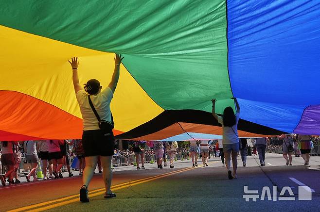 [내슈빌=AP/뉴시스] 28일(현지 시간) 미 테네시주 내슈빌에서 열린 연례 LGBTQ+ 내슈빌 프라이드 행진 참가자들이 대형 무지개 깃발을 들고 있다. 2025.06.29.