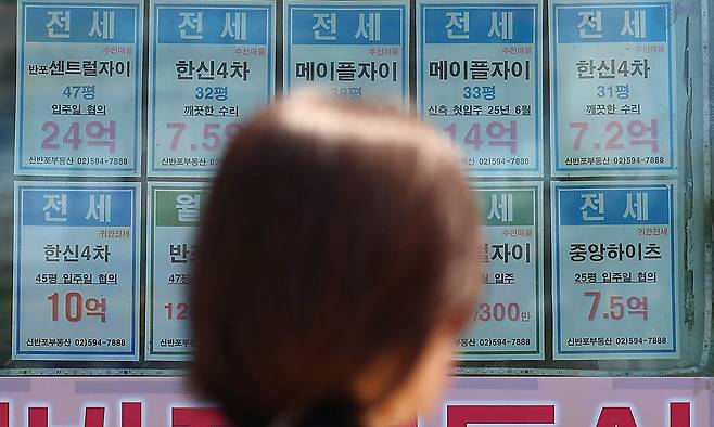 지난 23일 서울 시내의 한 공인중개사사무소에 붙은 전세 매물 안내문 앞으로 시민이 지나가고 있다. 연합뉴스