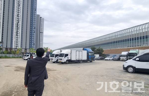 용인 보평역 스타힐스 조합원 입주민이 일반분양보다 조합아파트가 비싼것에 대한 이유를 지적하며 방음벽과 아파트를 가리키고 있다.사진=김형운 기자