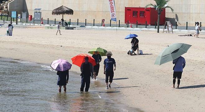 전국적으로 무더위가 이어진 30일 오후 경남 창원시 마산합포구 광암해수욕장에서 양산을 쓴 시민이 산책하며 무더위를 식히고 있다./연합뉴스