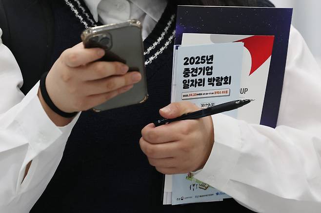 서울 강남구 코엑스에서 열린 2025 중견기업 일자리 박람회를 찾은 구직자가 기업 관련 소책자들을 들고 이동하고 있다./연합뉴스