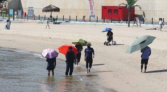 전국적으로 무더위가 이어진 30일 오후 경남 창원시 마산합포구 광암해수욕장에서 양산을 쓴 시민이 산책하며 무더위를 식히고 있다. 사진=연합뉴스