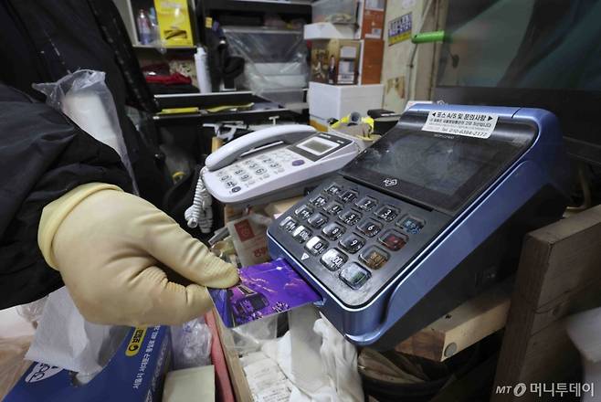 [서울=뉴시스] 김근수 기자 = 14일 서울 시내의 한 점포에서 점주가 신용카드로 물건을 결제하고 있다.   금융위원회는 '2025년 상반기 영세·중소가맹점 선정 결과’를 통해 영세·중소신용카드가맹점들의 신용·체크카드 수수료 부담이 기존보다 0.05∼0.10%p 낮아진다.  올해 상반기 신용카드가맹점 305만9000개, 결제대행업체 하위가맹점 181만5000개, 택시사업자 16만6000개에 우대수수료율을 적용키로 했다고 밝혔다. 2025.02.14. ks@newsis.com /사진=김근수