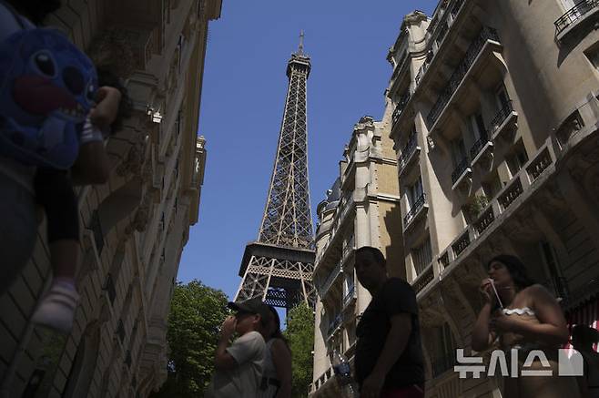 [파리=AP/뉴시스]1일(현지 시간) 프랑스 파리에서 관광객들이 에펠탑 아래를 지나고 있다. 2025.07.02.