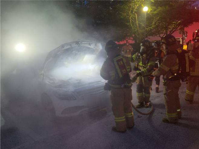 1일 부산 수영구의 한 아파트 앞 주차장에 세워둔 벤츠 차량에서 불이 나 소방대원들이 진화 작업을 벌이고 있다. 부산소방재난본부 제공