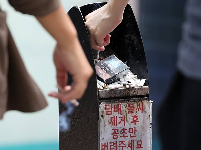 서울 종로구 흡연구역에서 시민들이 담배꽁초를 재떨이에 버리는 모습. /뉴스1
