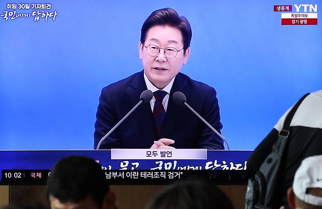 3일 오전 서울역 대합실에서 시민들이 이재명 대통령 ‘취임 한달’ 기자회견 생중계 영상을 시청하고 있다. 뉴스1