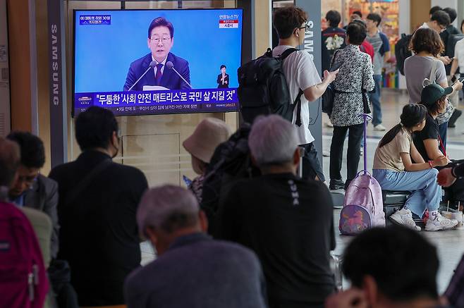 이재명 대통령의 첫 기자회견이 진행된 3일 중구 서울역에서 시민들이 방송을 지켜보고 있다. [연합]
