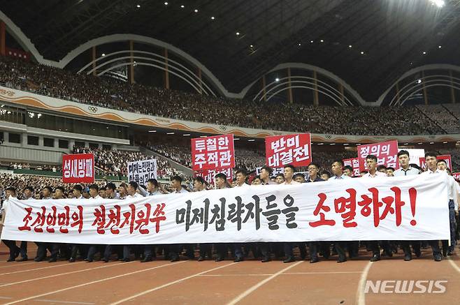 [평양=AP/뉴시스] 6월 25일 북한 평양의 5월 1일 경기장에서 열린 '미제 반대 투쟁의 날'(6·25) 기념집회에 참석한 북한 주민들이 현수막과 손팻말을 들고 구호를 외치고 있다. 2024.07.03.