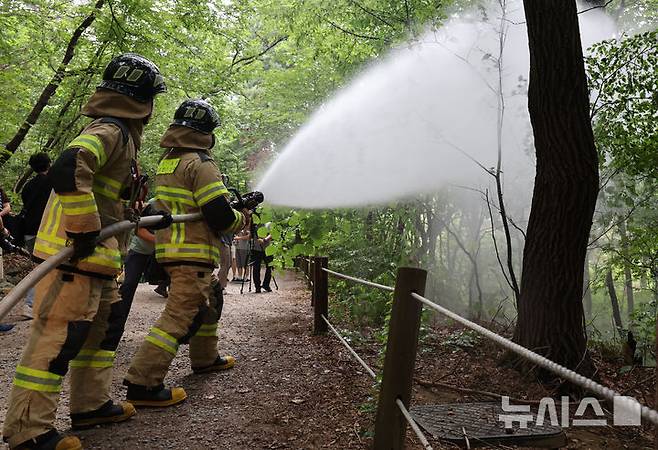 [서울=뉴시스] 권창회 기자 = 3일 서울 노원구 삼육대학교 인근 제명호에서 서울소방 관계자들이 '러브버그(붉은등우단털파리)' 방제작업을 하고 있다. 2025.07.03. kch0523@newsis.com