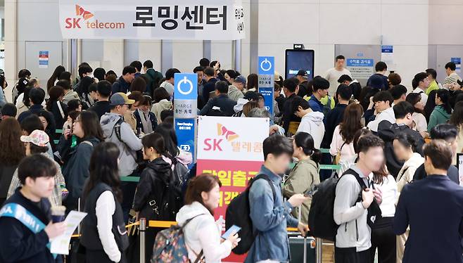 Travelers wait to replace SIM cards at the SK Telecom roaming center at Incheon International Airport on May 1. /News1
