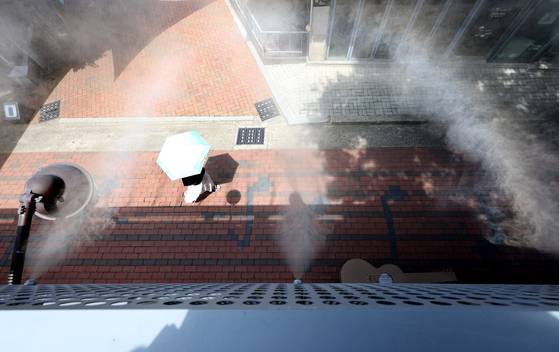 폭염이 연일 계속된 4일 대구 중구 김광석다시그리기길에 설치된 쿨링포그(안개형 냉각수) 아래로 한 시민이 양산을 쓰고 이동하고 있다. 뉴시스