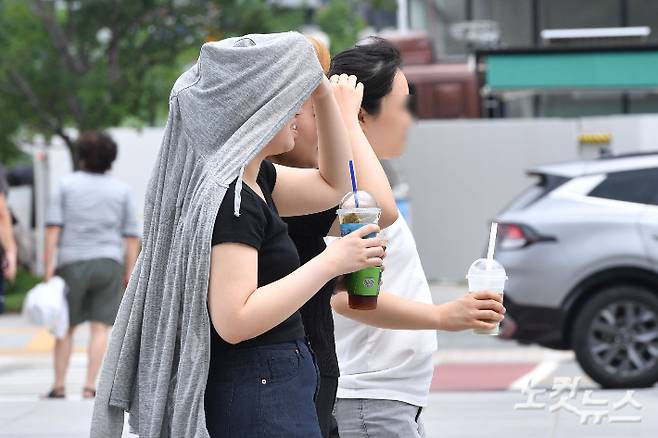 서울에 올해 첫 폭염주의보가 내려진 30일 오후 서울 종로구 광화문 광장에서 시민들이 옷으로 햇빛을 가리고 있다. 류영주 기자