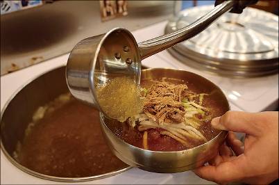 (4) 고명과 매운 양념장을 메밀면에 올린 뒤 차가운 육수를 붓는다.