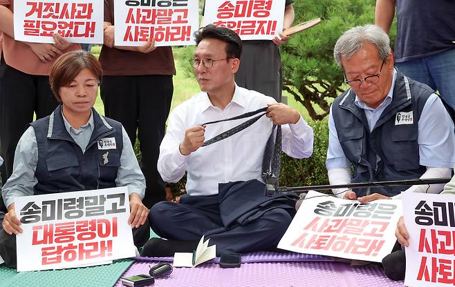 김민석 국무총리가 취임 후 첫 일정으로 4일 서울 용산구 대통령실 앞에서 송미령 농림축산식품부 장관 유임 결정 철회를 촉구하며 항의 농성 중인 농민단체와 면담에 앞서 넥타이를 벗고 있다.