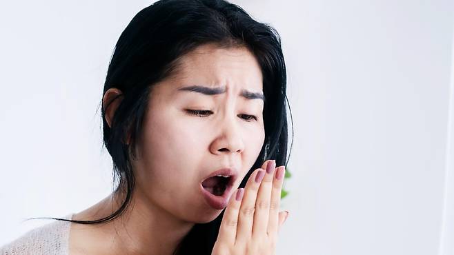 한 여성이 자신의 입냄새를 확인하려고 손을 입 앞에 대고 숨을 내쉰다