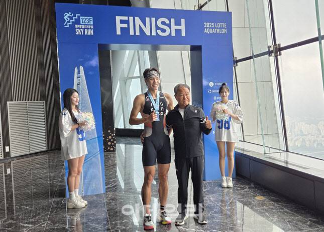 6일 서울 송파구 롯데월드타워 123층에서 열린 ‘2025 롯데 아쿠아슬론’ 결승 지점에서 종합 1위를 차지한 장현일 씨(왼쪽)가 맹호승 대한철인3종협회장과 함께 기념 촬영을 하고 있다. (사진=한전진 기자)