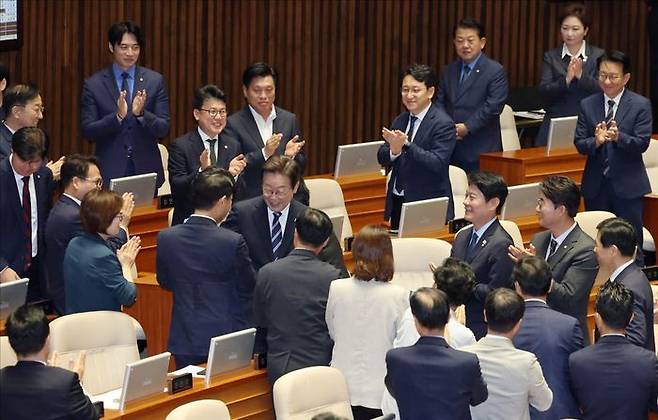 이재명 대통령이 지난달 26일 국회 본회의장에서 추가경정예산안에 대한 시정연설을 위해 입장하며 민주당 의원들과 인사하고 있다. ⓒ국회사진기자단