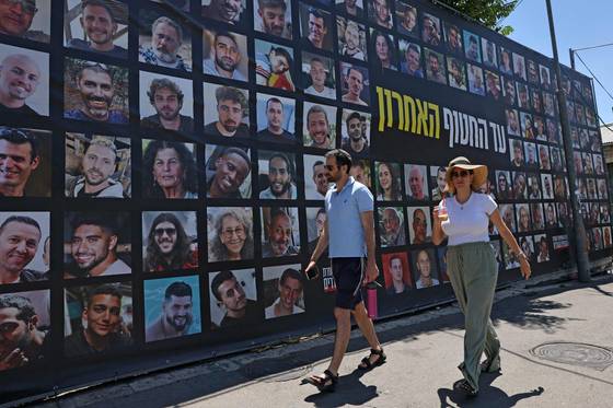 7일(현지시간) 이스라엘 수도 예루살렘에서 가자지구에 억류된 이스라엘 인질들의 초상화가 그려진 광고판 앞을 사람들이 지나가고 있다. AFP=연합뉴스