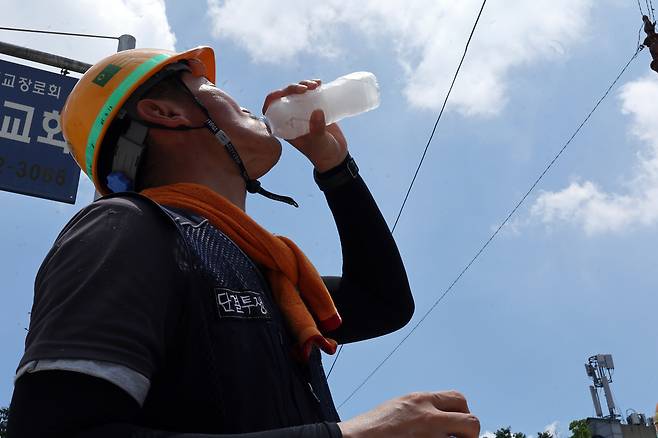 엿새째 폭염특보가 내려진 2일 광주 서구 금호동 한 공사장 앞에서 한 건설노동자가 더위를 달래기 위해 얼음물을 마시고 있다.[연합]