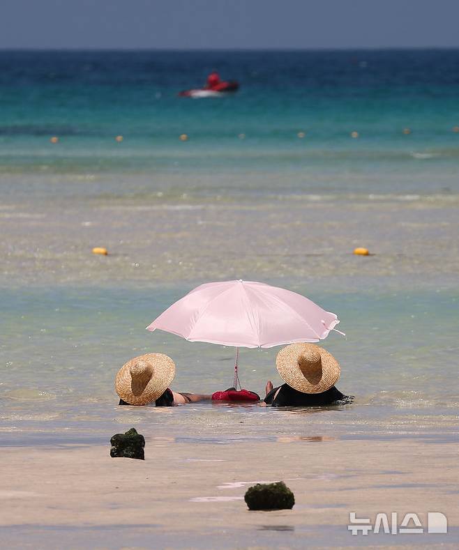 [제주=뉴시스] 우장호 기자 = 폭염의 기세가 수그러들지 않는 6일 오후 제주시 한림읍 금능해수욕장을 찾은 피서객들이 시원한 바닷물에 발을 담그며 더위를 식히고 있다. 2025.07.06. woo1223@newsis.com