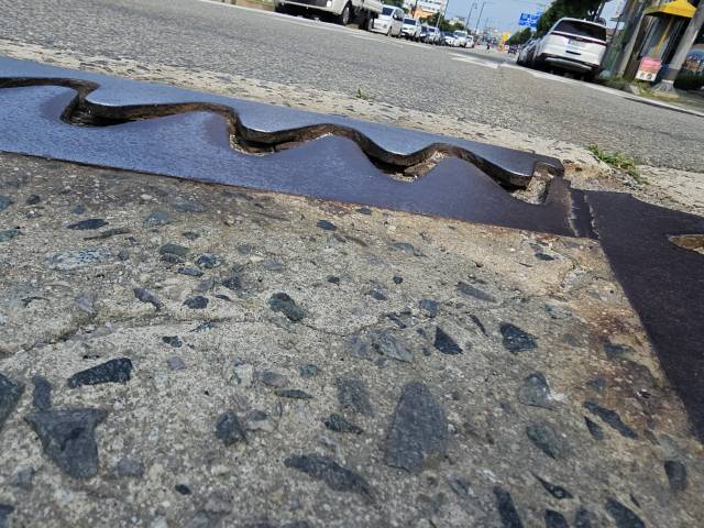 충주 도심 천변도로 성내교 구간의 신축 조인트 철판이 하늘로 들려 올라간 모습. 지나가는 차량들이 철판 위를 지날 때마다 덜컹거리며 충격이 발생해 운전자들이 불편을 겪고 있다.사진=김의상 기자