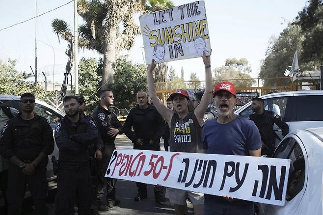 베냐민 네타냐후 이스라엘 총리와 부인 사라 여사가 3일(현지 시간) 이스라엘-가자 접경지대 인근 니르 오즈 키부츠를 방문한 가운데 하마스에 억류된 인질들의 가족과 지지자들이 그들의 석방을 촉구하는 손팻말을 들고 시위하고 있다. 네타냐후 총리는 하마스 무장세력이 공격을 감행한 2023년 10월 7일 이후 처음으로 이곳을 방문했고 당시, 이 지역 주민 상당수가 살해되거나 납치됐다. 2025.07.04. 니르 오즈=AP/뉴시스