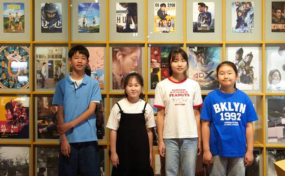 영화 기념품 공간에 전시된 영화 포스터 앞에서 포즈를 취한 소중 학생기자단.