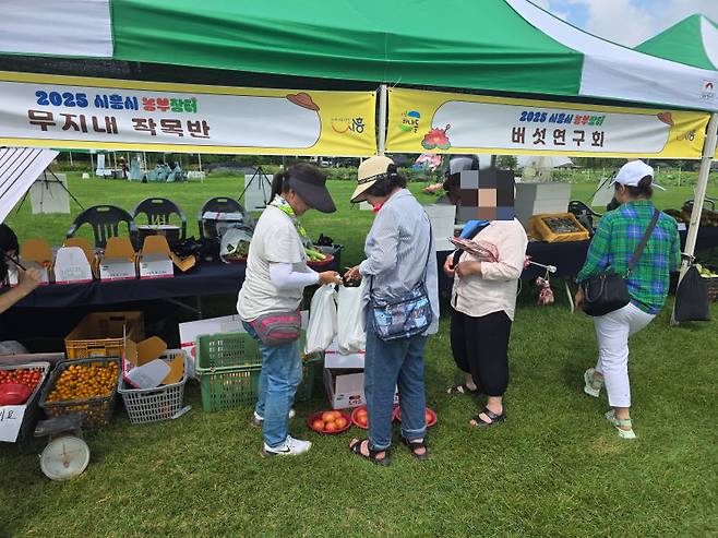 지난 5일 시흥시 연꽃테마파크 잔디광장에서 열린 '농부장터'에서 산책 온 방문객들이 농산물을 구입하고 있다./사진=이민호기자