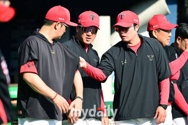 KIA 김민우 코치가 손승락 코치의 유니폼을 만져보고 있다.