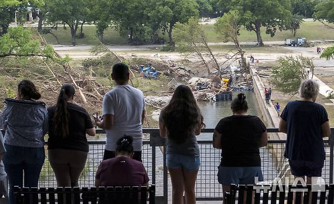 [커빌=AP/뉴시스] 6일(현지 시간) 미 텍사스주 커빌에서 주민들이 홍수 피해를 입은 과달루페강 일대를 내려다보고 있다. 텍사스주를 강타한 폭우와 홍수로 지금까지 사망자는 71명, 실종자는 최소 41명으로 늘어났다. 2025.07.07.