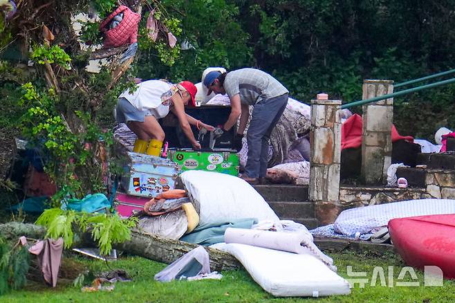 [헌트=AP/뉴시스] 6일(현지 시간) 미 텍사스주 헌트에서 사람들이 급류성 홍수가 휩쓸고 간 과달루페 강변의 기독교 청소년 캠프 '미스틱 야영장'에서 피해 물품을 조사하고 있다. 텍사스주를 강타한 폭우와 홍수로 지금까지 사망자는 최소 80명, 실종자는 41명으로 늘어났다. 2025.07.07.