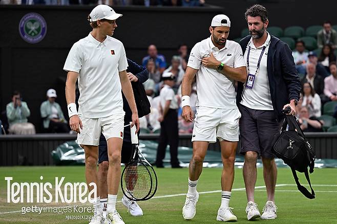 가슴을 부여 잡고 토너먼트 닥터의 부축을 받으며 퇴장하고 있는 디미트로프 (사진/게티이미지코리아)
