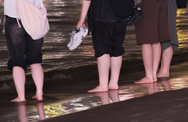 열대야가 이어진 7일 오후 부산 광안리해수욕장에서 시민들이 시원한 파도에 발을 담그고 있다. 연합뉴스 제공