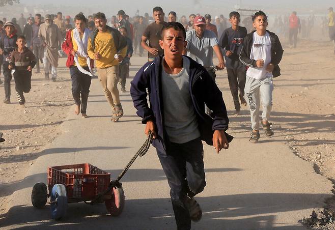 5월29일(현지시각) 가자 주민들이 가자 남부 칸 유니스에 있는 가자인도주의재단에서 배급하는 구호품을 받기 위해 뛰고 있다. 칸유니스/로이터 연합뉴스