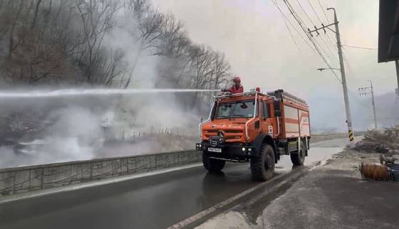 A high-performance fire extinguishing truck disperses water on flames in Andong City in North Gyeongsang on March 25. [KOREA FOREST SERVICE]