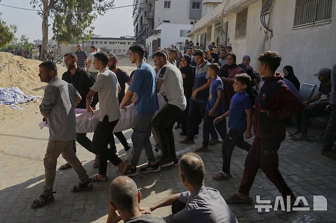 [가자시티=AP/뉴시스]  가자지구 가자시티 알시파 병원 인근에서 6월 11일 팔레스타인 주민들이 전날 밤 인도적 지원을 받으려다 숨진 사람의 시신을 옮기고 있다. 팔레스타인 보건부는 가자 인도주의재단(GHF) 구호품을 받으려 필사적으로 접근하던 팔레스타인 난민들이 이스라엘군(IDF)의 총격을 받아 36명이 숨지고 207명이 부상했다고 6월12일 밝혔다. 2025.07.08.